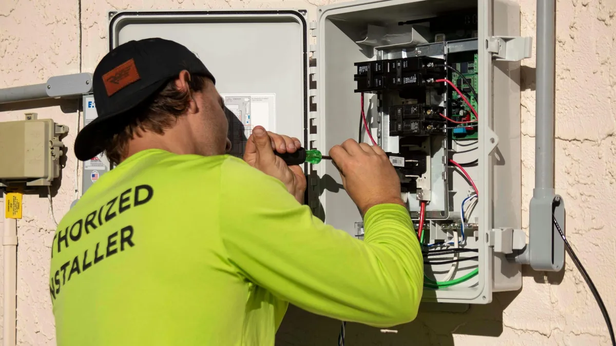 Technician installing an outdoor backup power/generator control panel on a home exterior — illustrative stock photo, not an actual Pahrump job site
